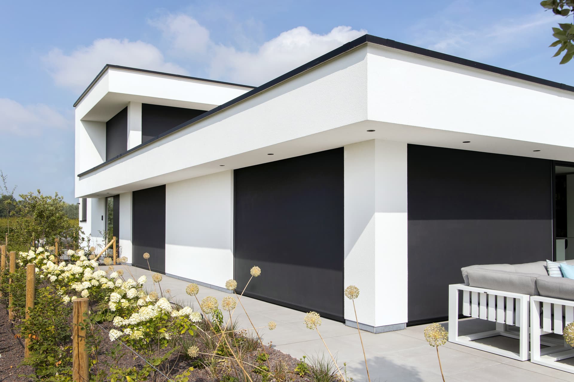 Brustor inbouw‑ZIP‑screens naadloos geïntegreerd in een moderne witte gevel, met windvaste zonwering voor grote ramen