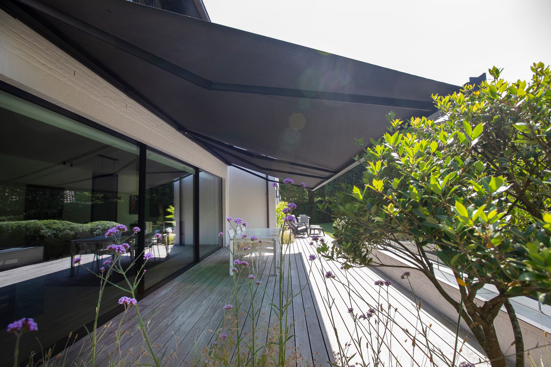Aluminium retractable awning in black finish installed above modern wooden terrace at contemporary home