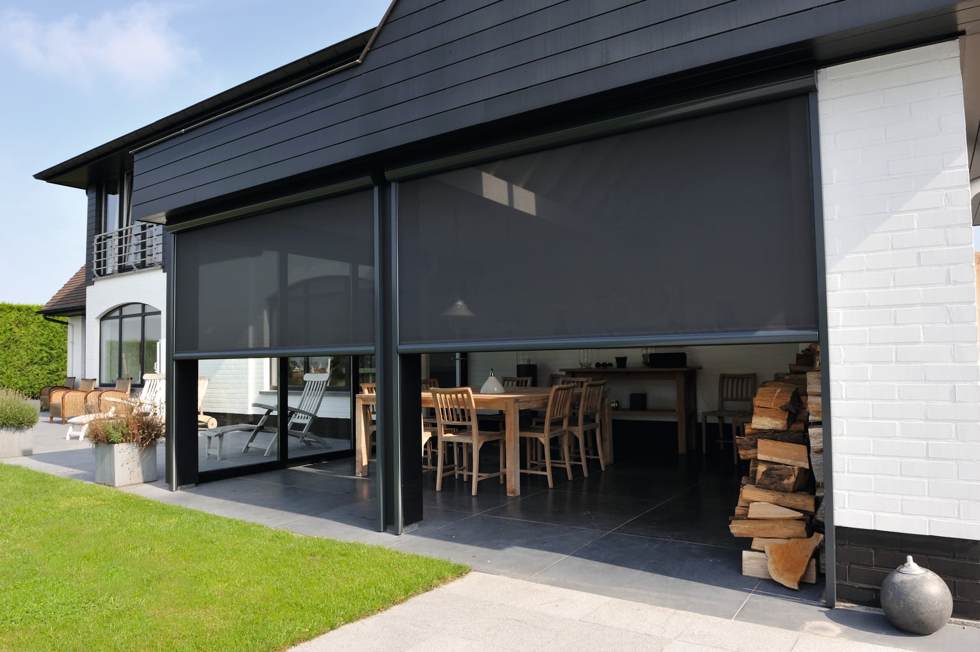 Aluminium zip screens in dark finish installed on contemporary home with open indoor‑outdoor dining area