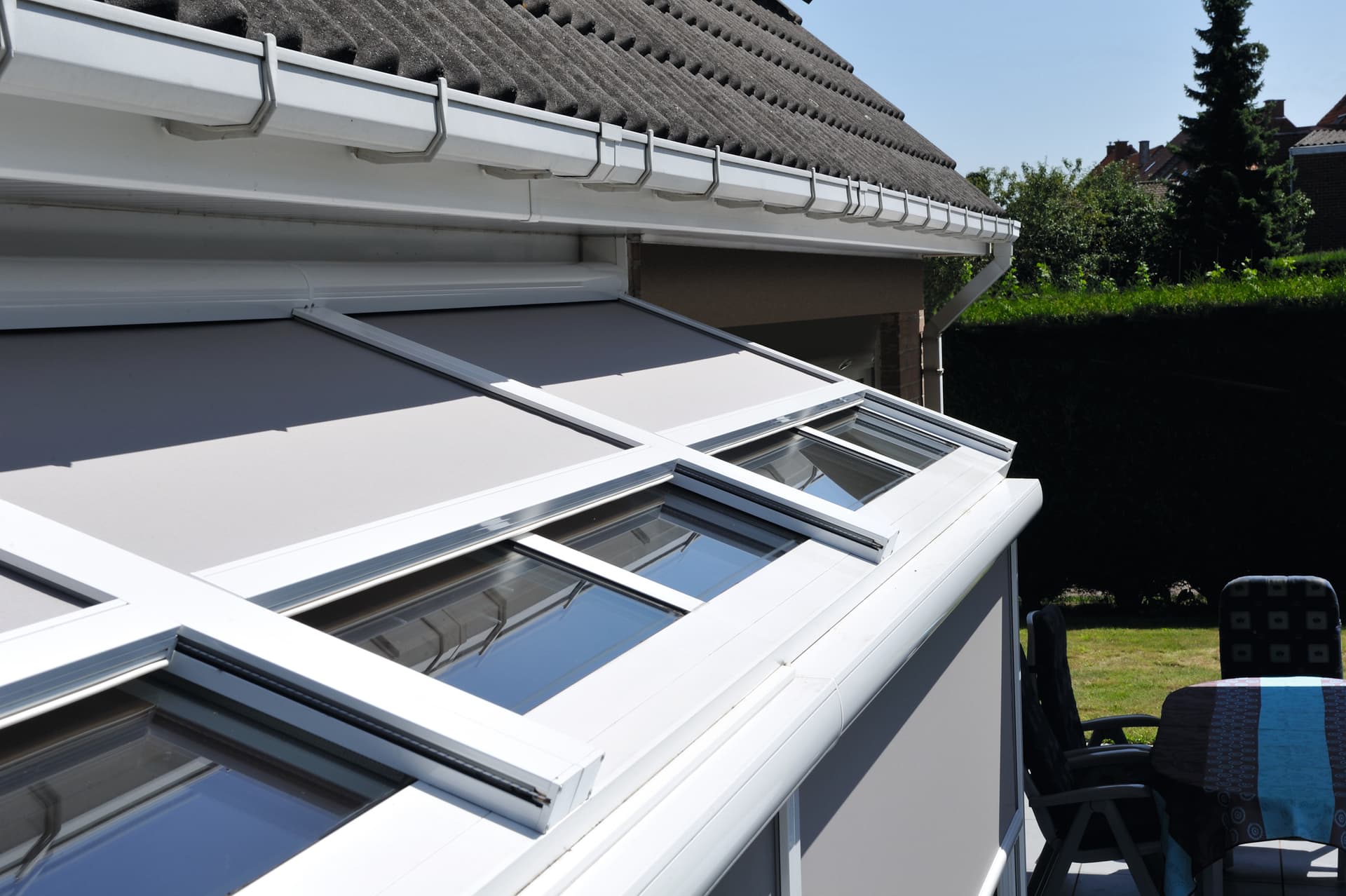Brustor Topscreen verandazonwering boven op een schuin glazen dak die buitenzonwering biedt voor een lichte veranda