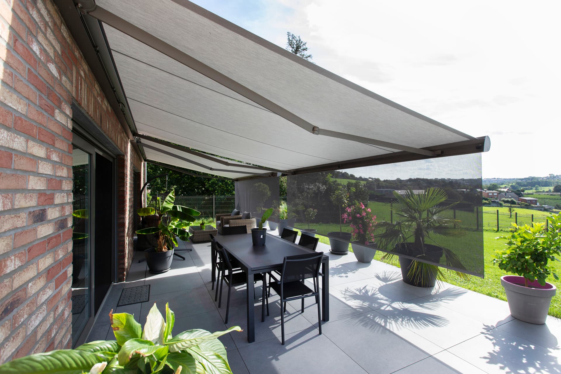 Brustor‑pergola met draaibare lamellen, geïntegreerde LED‑verlichting, ZIP‑screens en terrasverwarmers die een beschutte buiten-eetruimte vormen