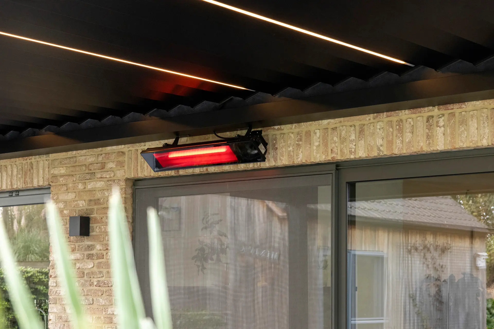 Aluminium pergola met geopend lamellendak dat een gestreept schaduwpatroon werpt over een buitenlounge op een zonnige dag.