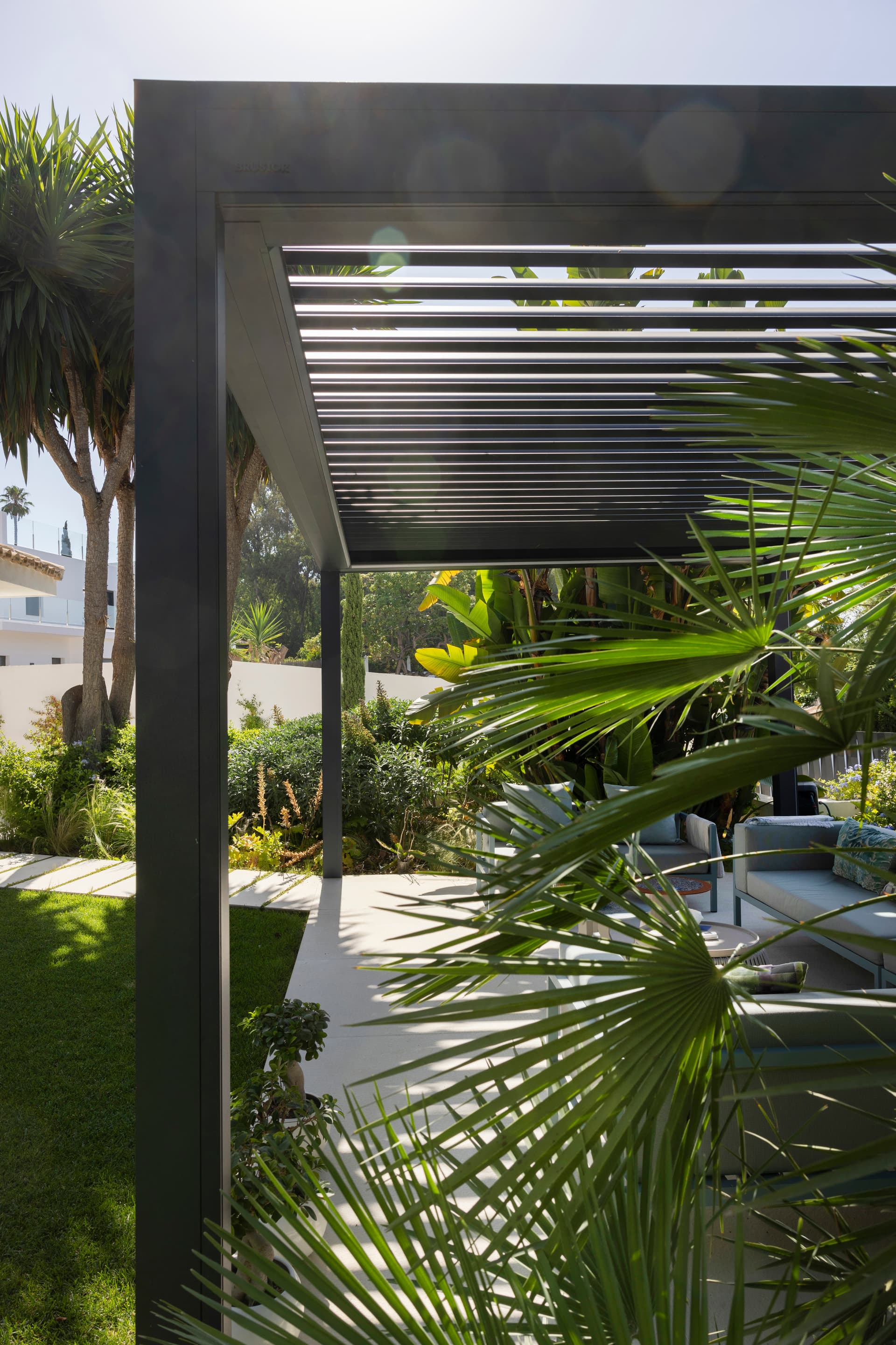 Aluminium louvred roof pergola in dark finish installed in contemporary tropical garden