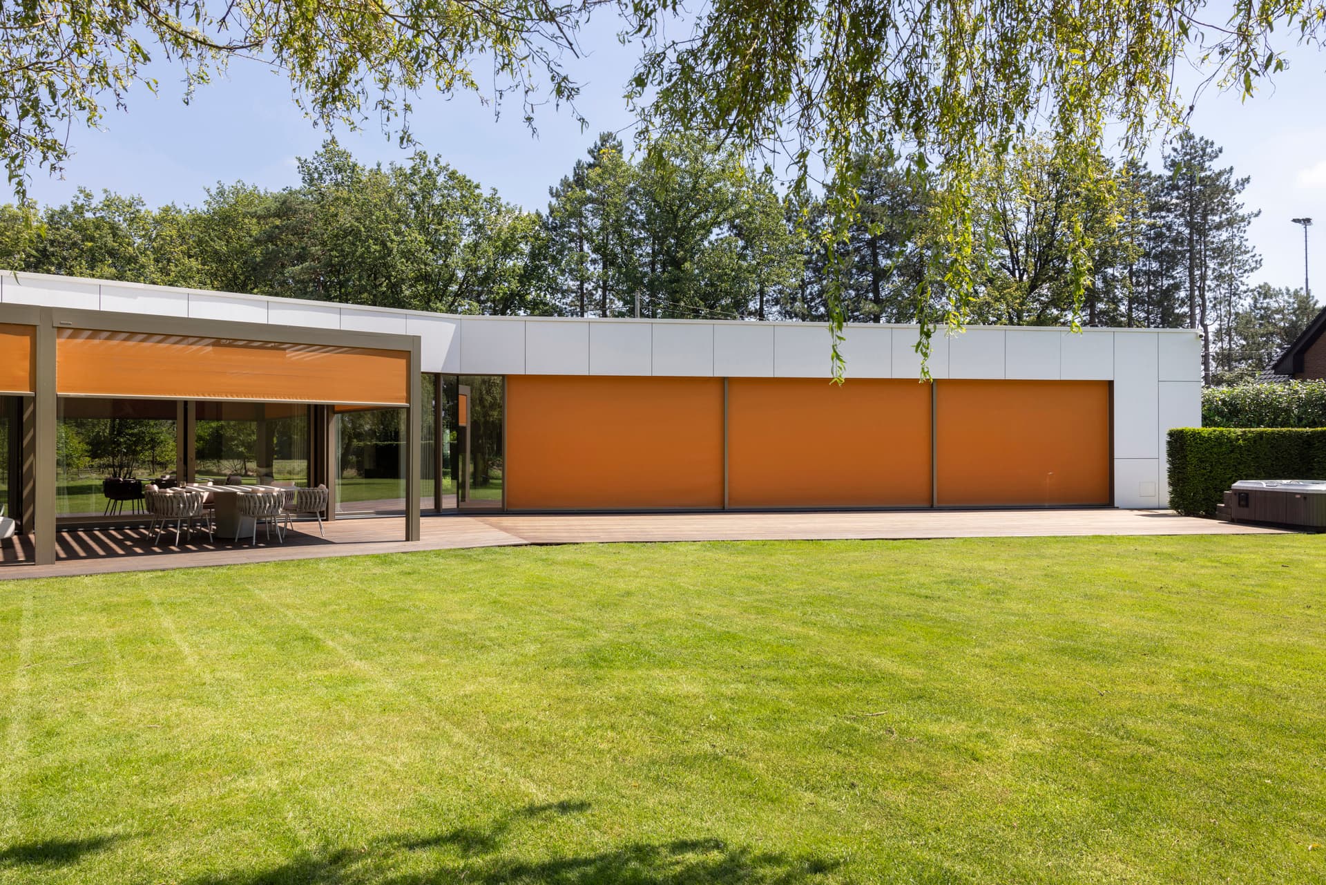 Aluminium zip screens in orange finish installed on contemporary home overlooking large garden
