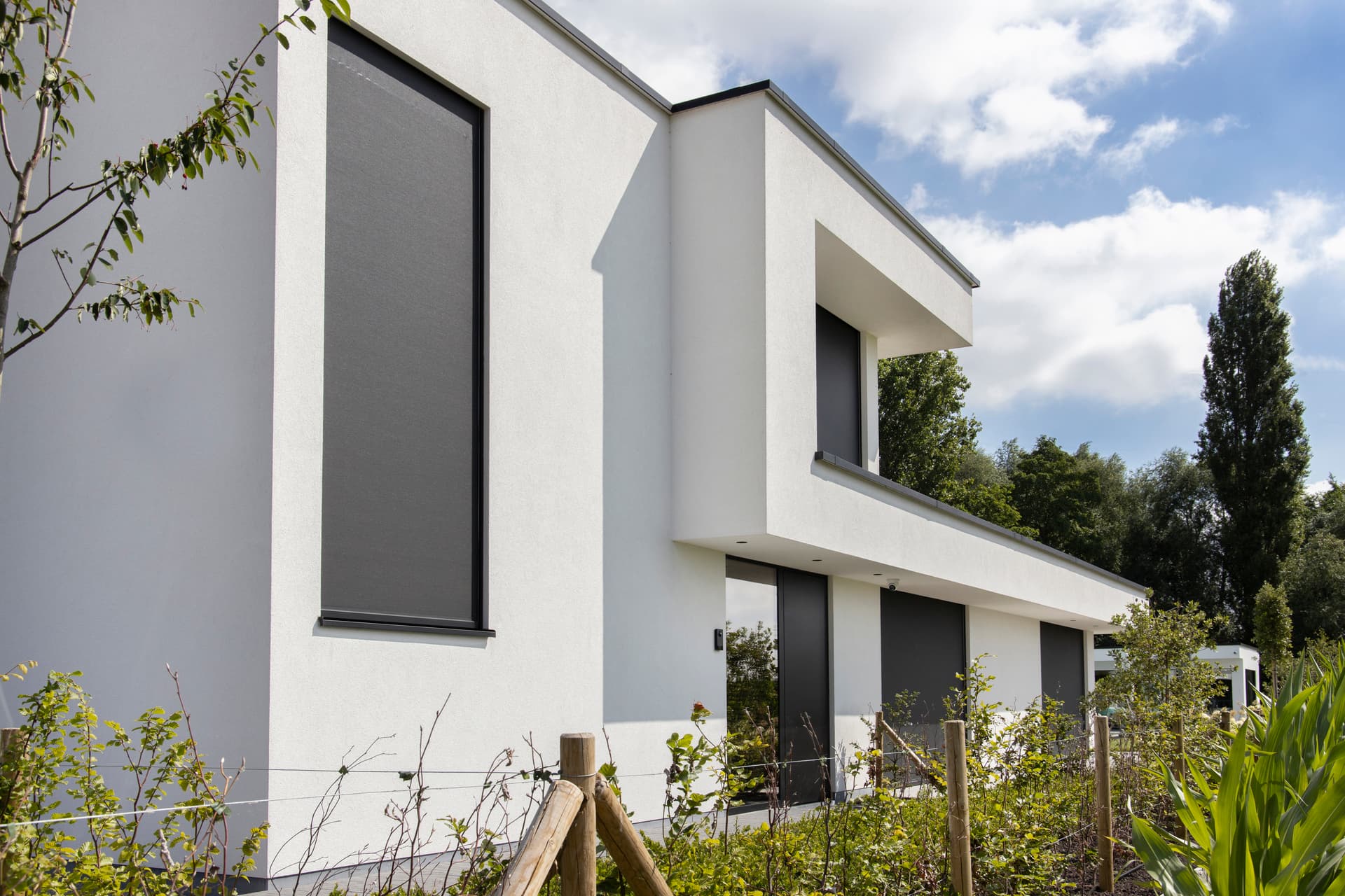 Aluminium zip screens in dark finish installed on contemporary white home façade