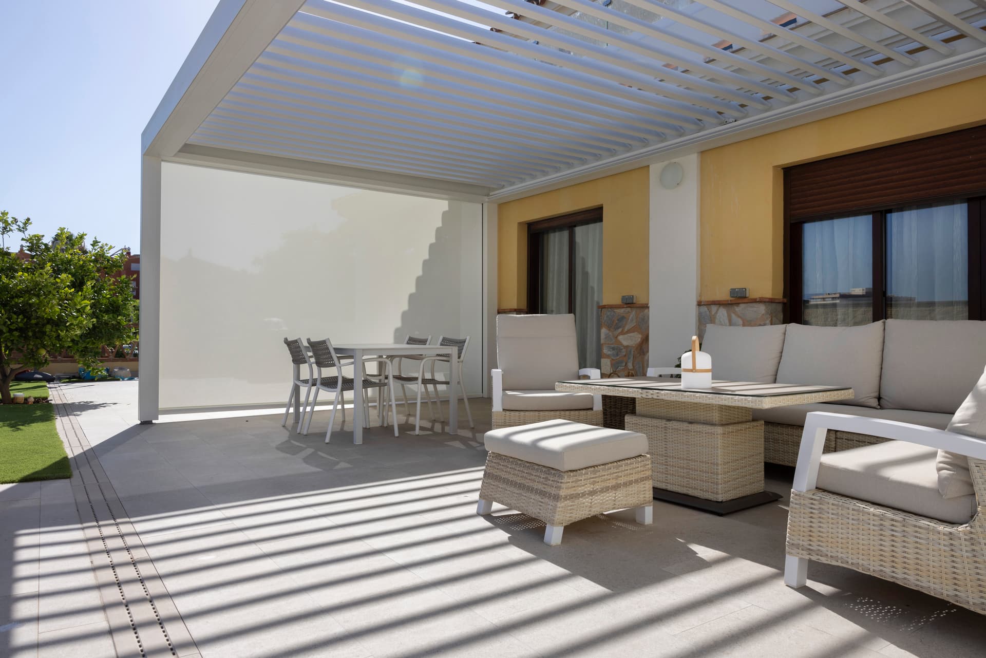 Aluminium louvred roof pergola in light finish installed above contemporary terrace with lounge and dining area